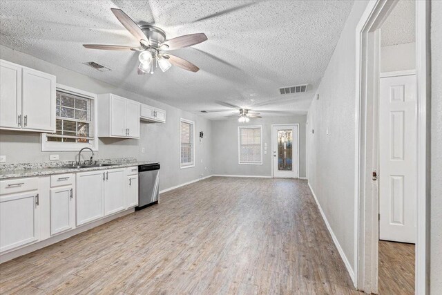 kitchen featuring sink, light hardwood / wood-style flooring, white cabinetry, a textured ceiling, and stainless steel dishwasher