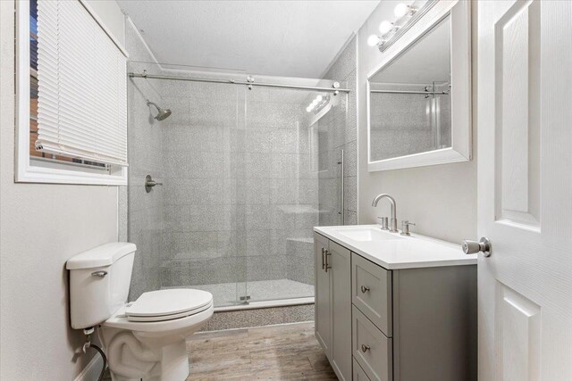 bathroom featuring vanity, hardwood / wood-style flooring, a shower with door, and toilet