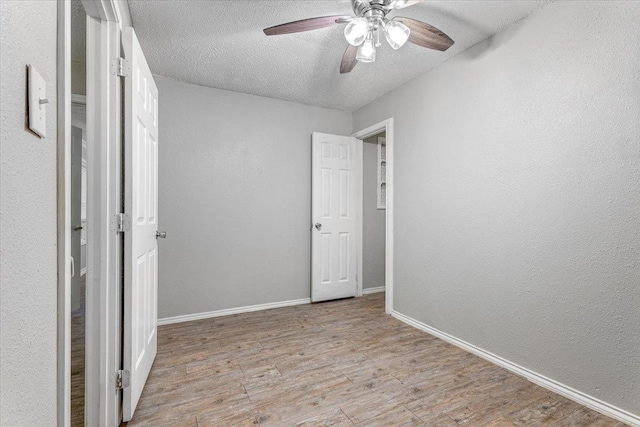 spare room featuring ceiling fan, light hardwood / wood-style flooring, and a textured ceiling