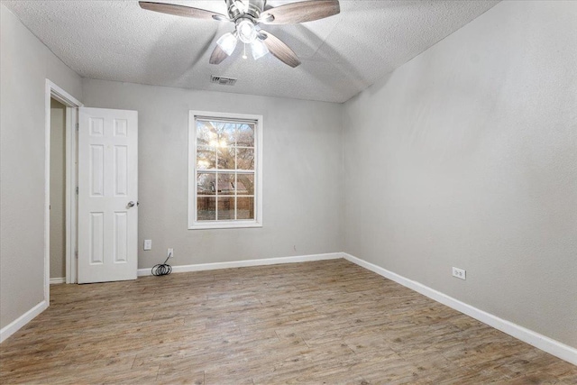 empty room with ceiling fan, a textured ceiling, and light wood-type flooring