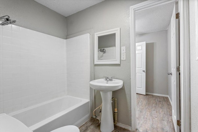 full bathroom featuring sink, hardwood / wood-style floors, shower / bathing tub combination, a textured ceiling, and toilet