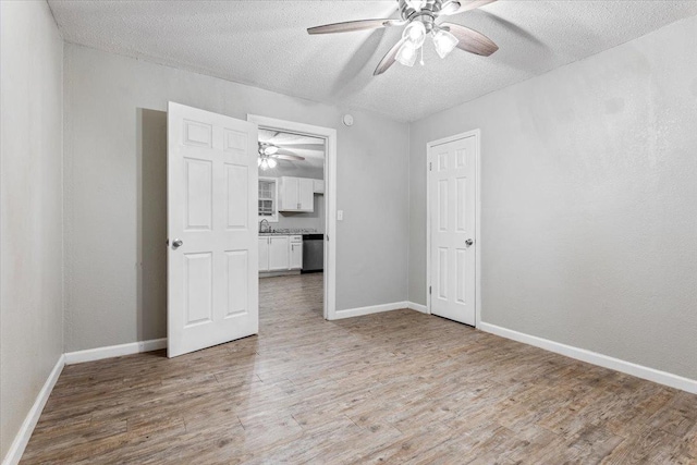 empty room featuring ceiling fan, sink, a textured ceiling, and light wood-type flooring