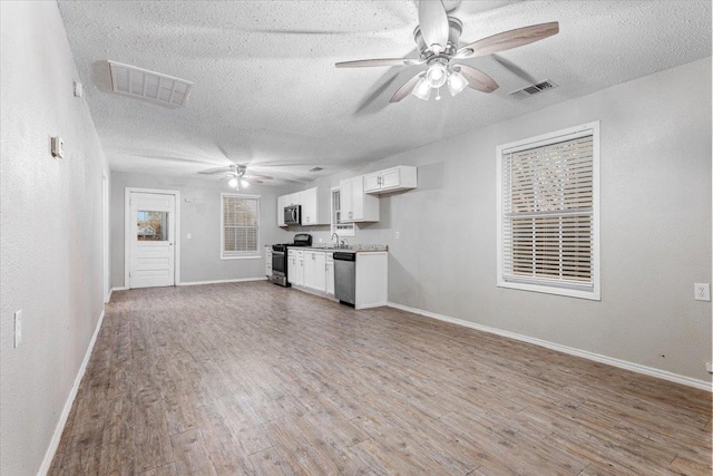 unfurnished living room with ceiling fan, wood-type flooring, sink, and a textured ceiling