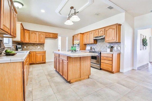 kitchen featuring hanging light fixtures, a kitchen island, tile countertops, and stainless steel stove