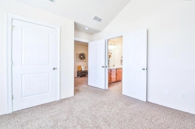 unfurnished bedroom with lofted ceiling, sink, ensuite bath, and light colored carpet