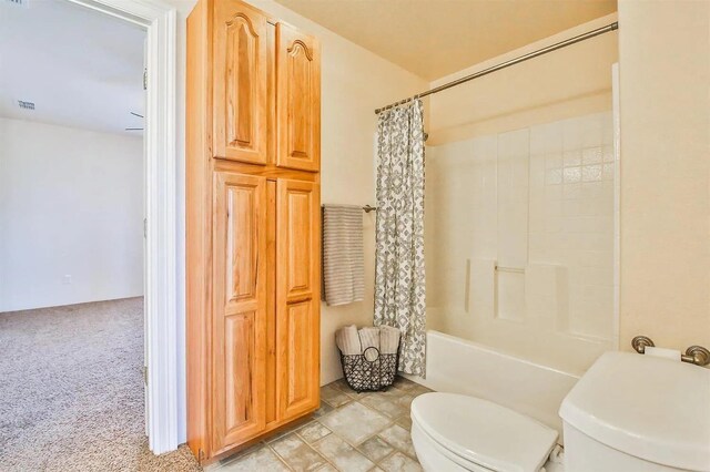 bathroom featuring shower / tub combo with curtain and toilet