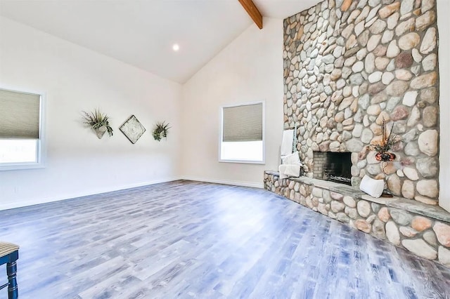 unfurnished living room with high vaulted ceiling, a stone fireplace, hardwood / wood-style floors, and beam ceiling