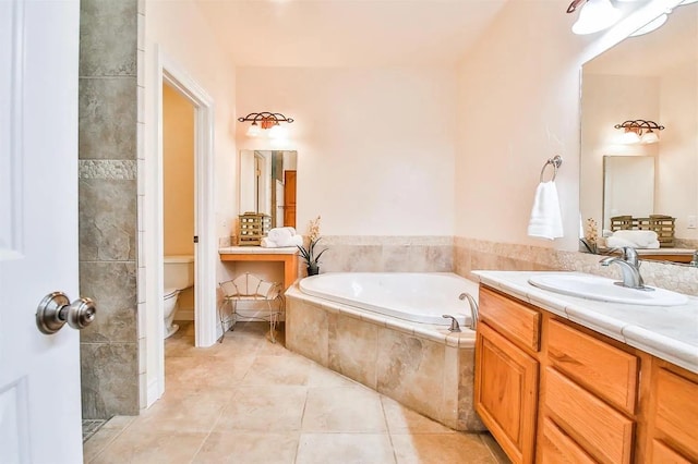 bathroom with tiled tub, vanity, tile patterned floors, and toilet