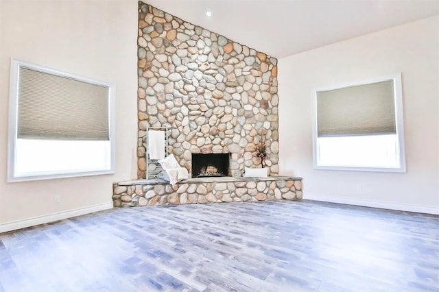 unfurnished living room with wood-type flooring, lofted ceiling, and a fireplace