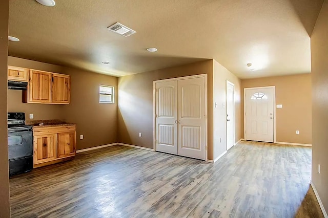 kitchen with range with electric cooktop, extractor fan, light hardwood / wood-style floors, and a textured ceiling