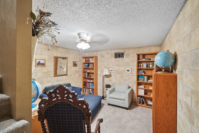 living area with light carpet, ceiling fan, and a textured ceiling