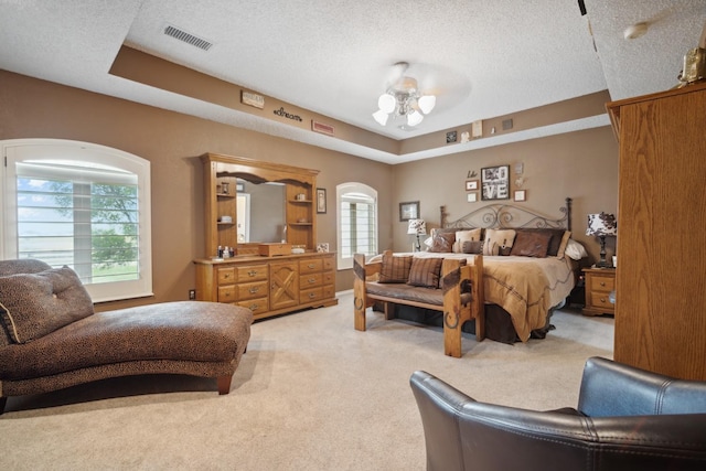 carpeted bedroom with ceiling fan, a raised ceiling, and a textured ceiling