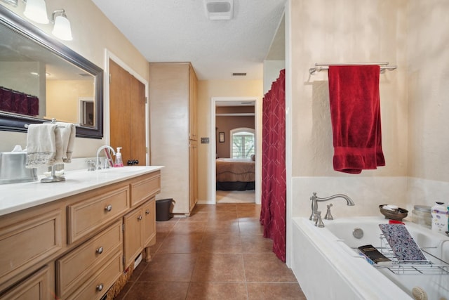 bathroom with vanity, tile patterned floors, a tub, and a textured ceiling