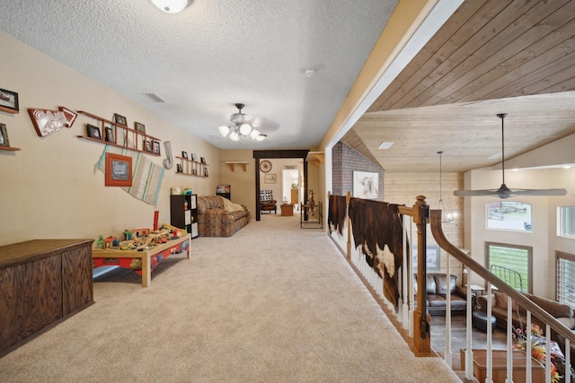 recreation room featuring light carpet, a textured ceiling, and ceiling fan