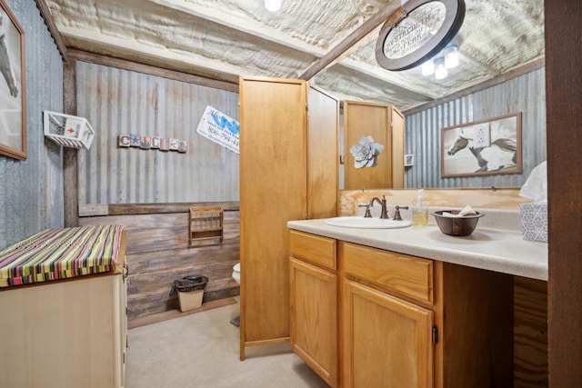 bathroom with wooden walls, vanity, and toilet