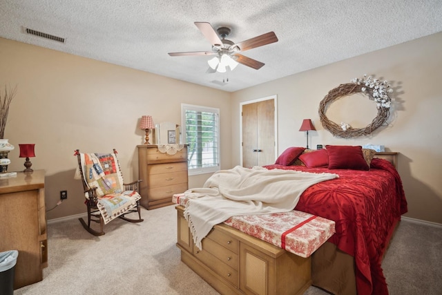 bedroom featuring ceiling fan, light colored carpet, and a textured ceiling