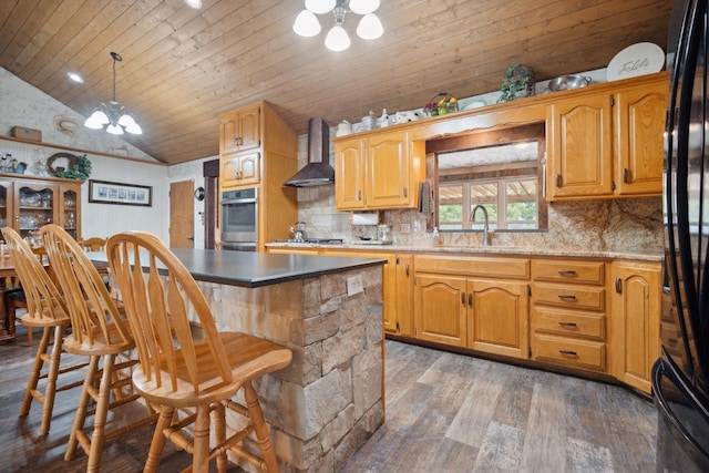 kitchen featuring lofted ceiling, sink, appliances with stainless steel finishes, an inviting chandelier, and wall chimney exhaust hood