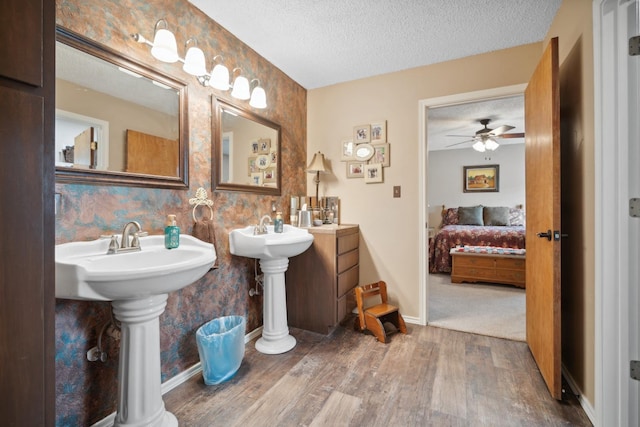 bathroom featuring ceiling fan, double sink, wood-type flooring, and a textured ceiling