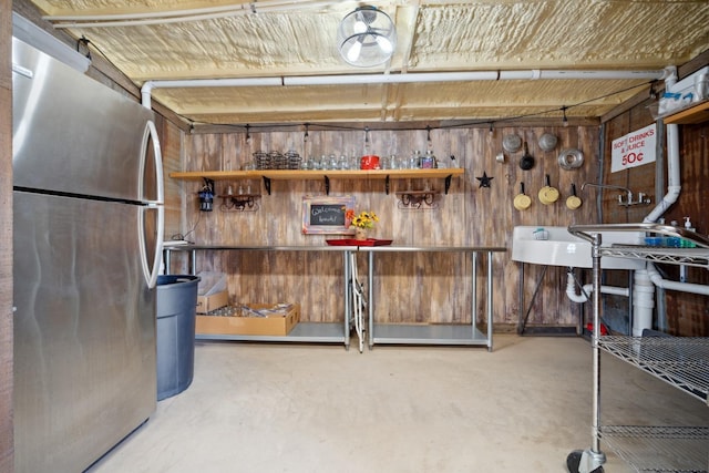 basement with wooden walls and stainless steel refrigerator