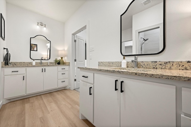 6937 12th St, Lubbock, TX 79416 - bathroom featuring visible vents, a sink, a shower, and wood finished floors