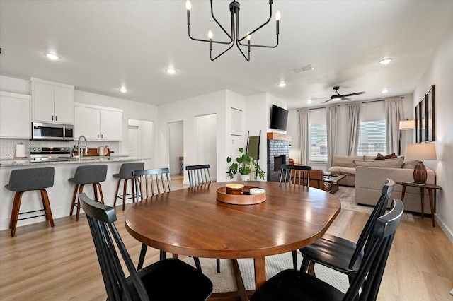 6937 12th St, Lubbock, TX 79416 - dining space featuring a fireplace, recessed lighting, light wood-type flooring, and ceiling fan with notable chandelier