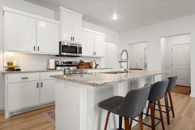 6937 12th St, Lubbock, TX 79416 - kitchen featuring light wood-style floors, decorative backsplash, a sink, and stainless steel appliances