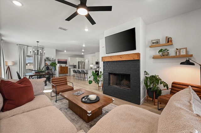 6937 12th St, Lubbock, TX 79416 - living area with ceiling fan with notable chandelier, visible vents, light wood-type flooring, and a fireplace