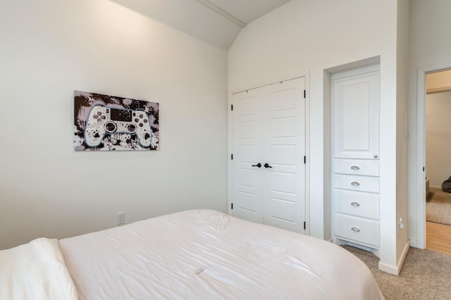 bedroom with vaulted ceiling, light colored carpet, and a closet