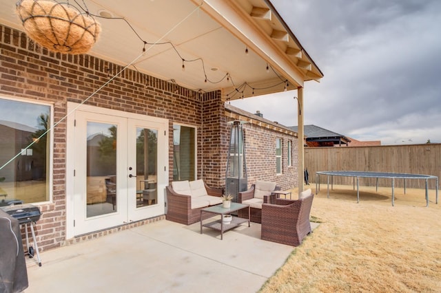 view of patio with french doors, a grill, and a trampoline