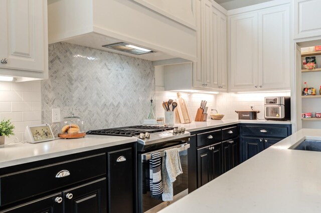 kitchen featuring white cabinetry, stainless steel range with gas stovetop, custom exhaust hood, and backsplash