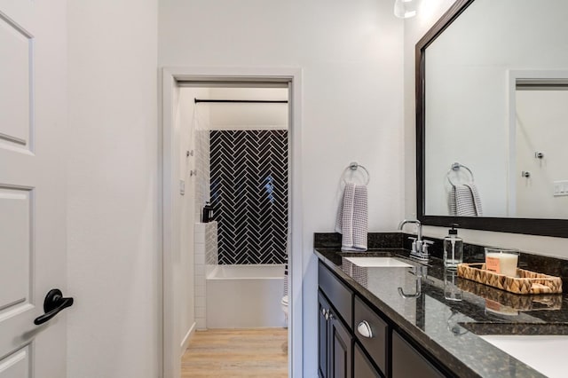 full bathroom with tiled shower / bath, vanity, toilet, and hardwood / wood-style floors