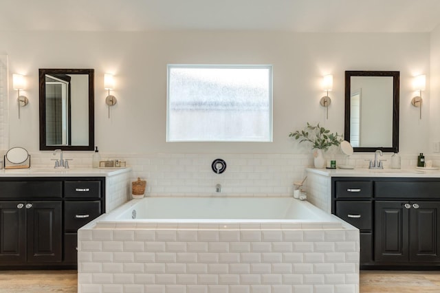 bathroom featuring hardwood / wood-style flooring, vanity, and tiled tub