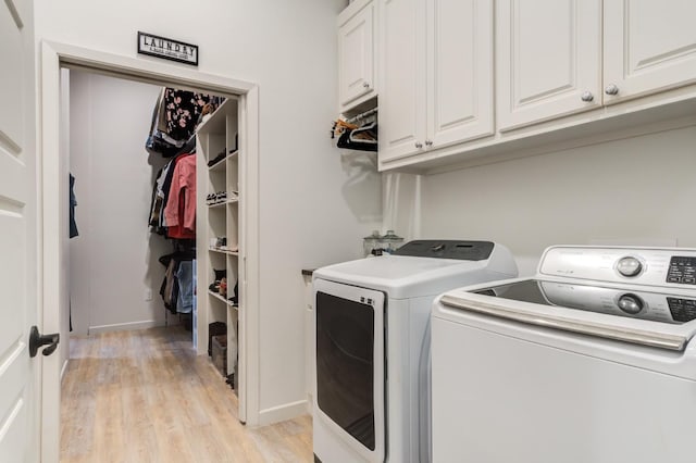 laundry area with cabinets, light wood-type flooring, and washer and clothes dryer