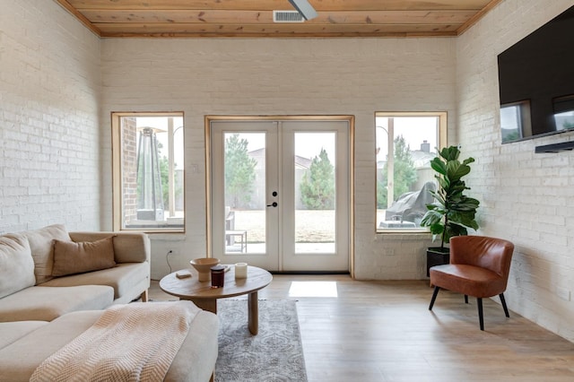 living room with french doors, brick wall, light hardwood / wood-style flooring, and wooden ceiling