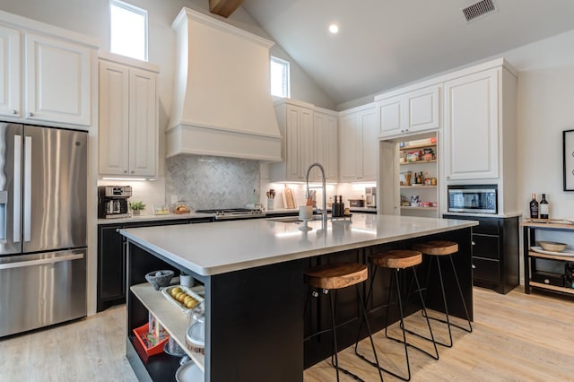 kitchen with an island with sink, white cabinetry, sink, custom exhaust hood, and stainless steel appliances