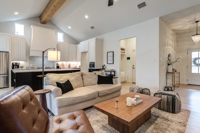 living room with an inviting chandelier, beam ceiling, high vaulted ceiling, and light wood-type flooring