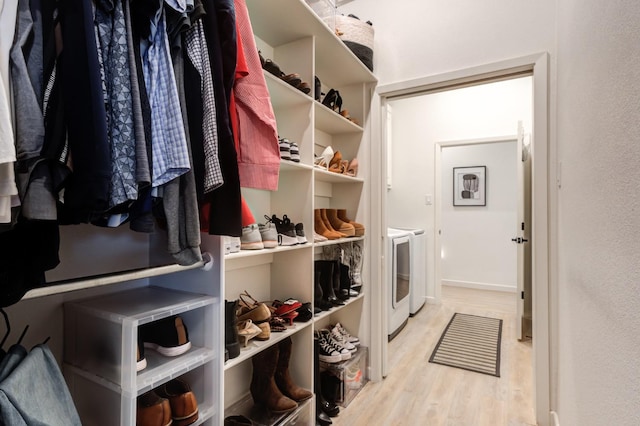 walk in closet with washer and clothes dryer and light hardwood / wood-style floors