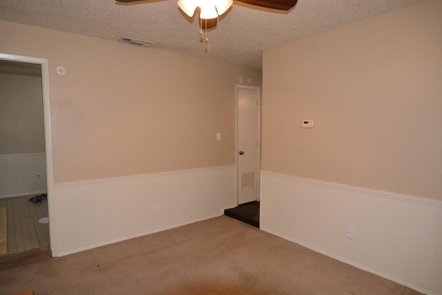 spare room featuring ceiling fan, light colored carpet, and a textured ceiling