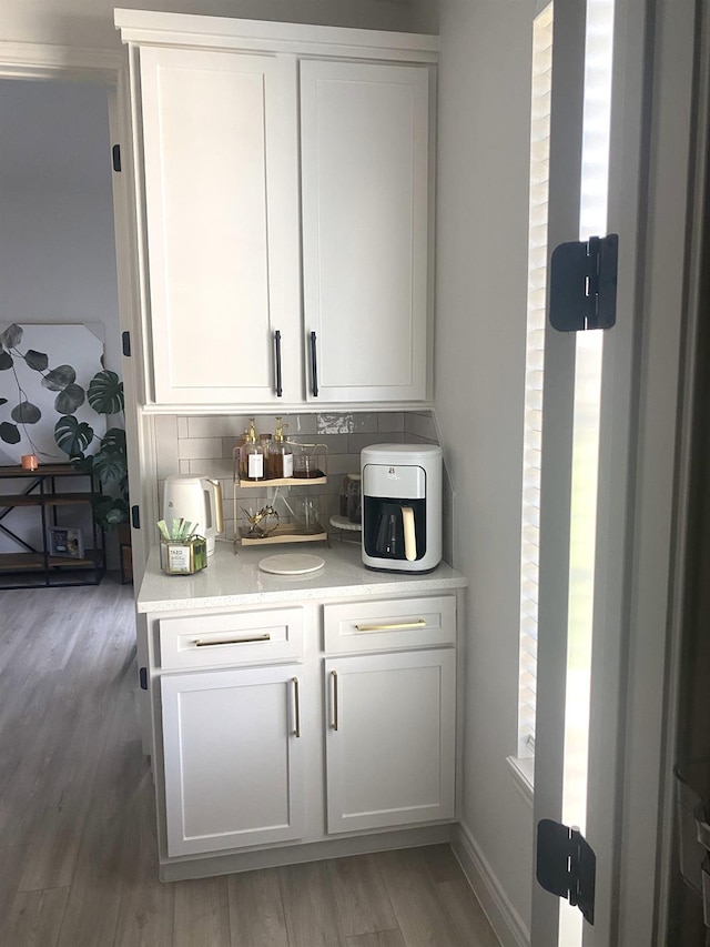 bar featuring white cabinetry, backsplash, and hardwood / wood-style floors