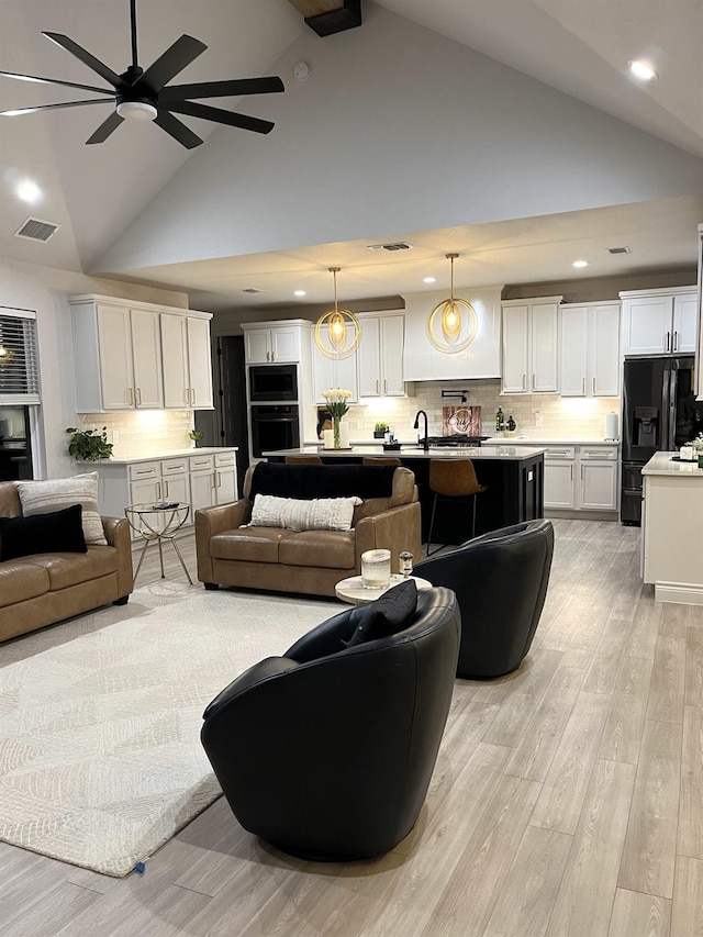 living room with high vaulted ceiling, sink, ceiling fan, and light hardwood / wood-style flooring