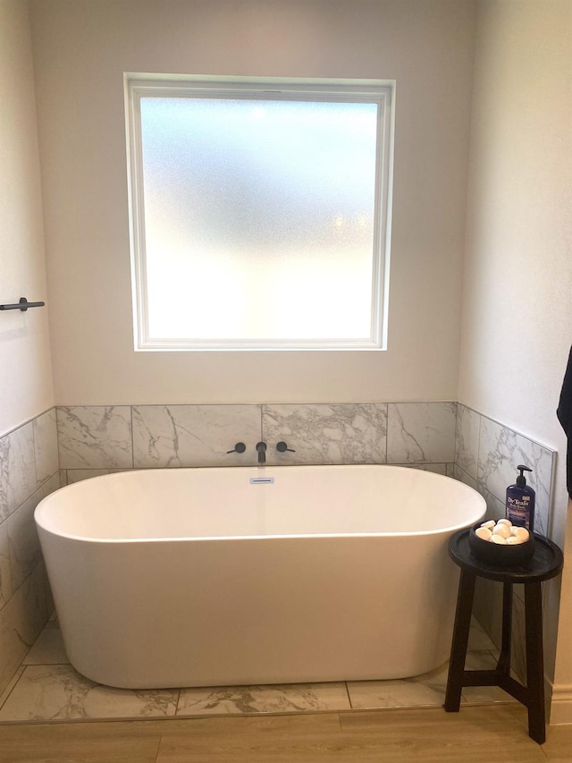 bathroom featuring a washtub, a wealth of natural light, and wood-type flooring