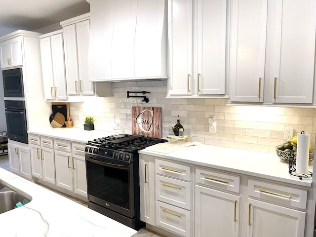 kitchen with black oven, range with gas stovetop, white cabinets, and custom exhaust hood