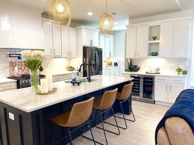 kitchen featuring wine cooler, pendant lighting, white cabinets, and appliances with stainless steel finishes