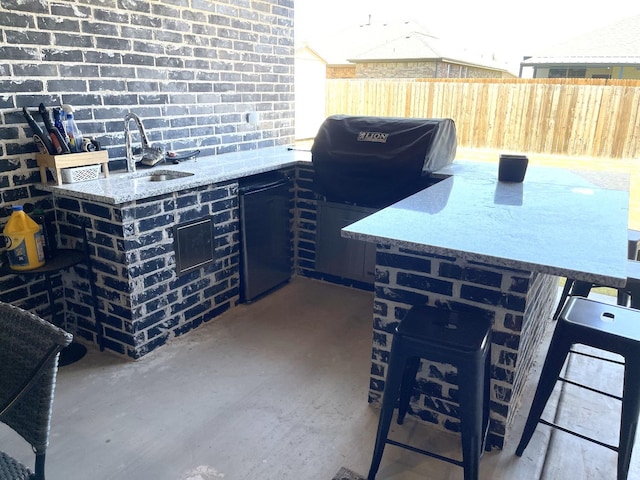 view of patio featuring area for grilling, a grill, and an outdoor wet bar