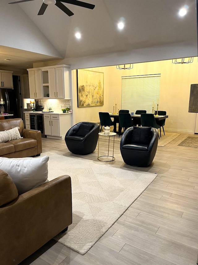 living room featuring wine cooler, ceiling fan, high vaulted ceiling, and light hardwood / wood-style flooring