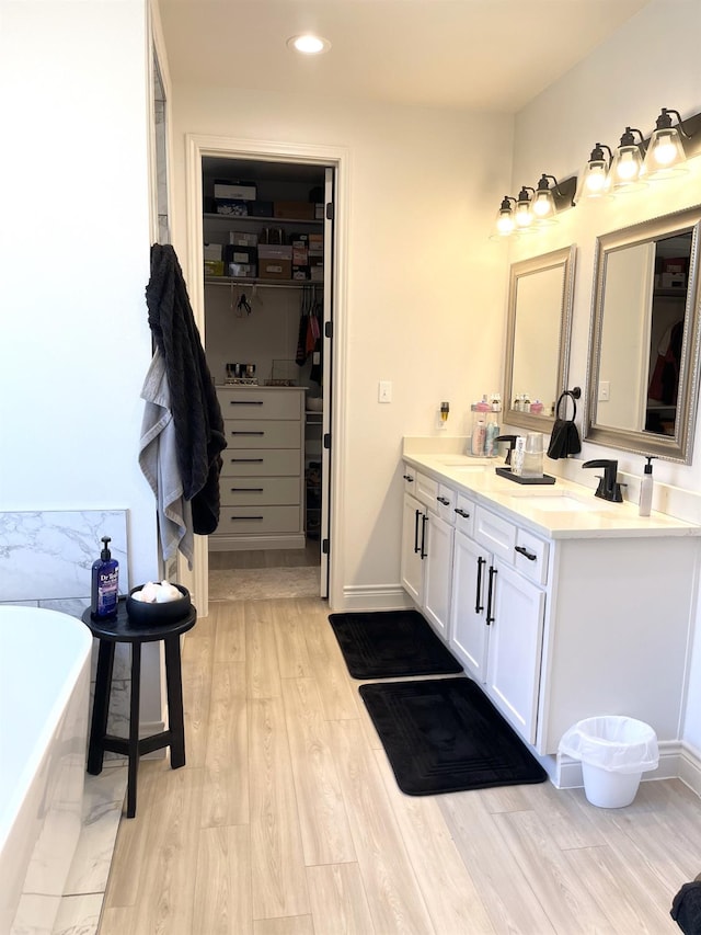 bathroom with hardwood / wood-style flooring, vanity, and a bath