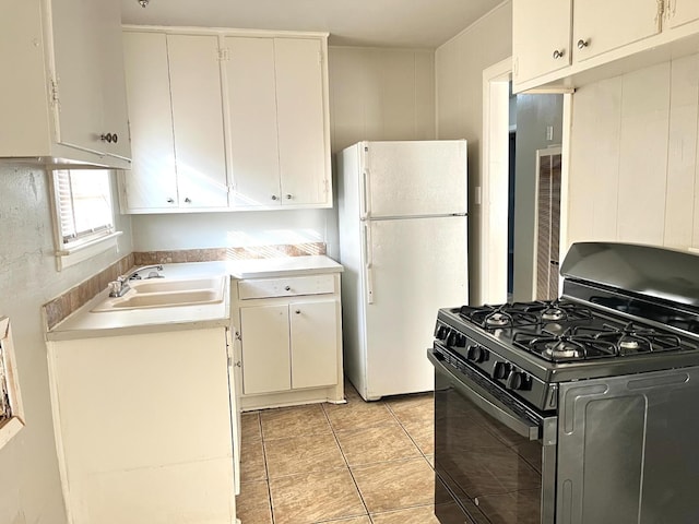 kitchen with white cabinetry, sink, white fridge, light tile patterned floors, and black gas range