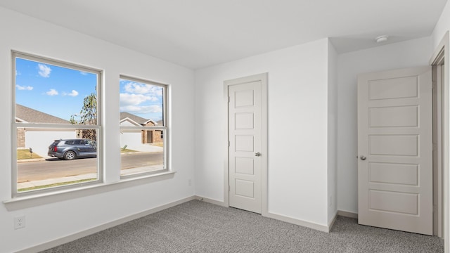spare room featuring light carpet and baseboards