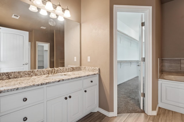 2007 County Rd 7560, Lubbock, TX 79423 - full bathroom featuring vanity, wood finished floors, a walk in closet, a garden tub, and baseboards