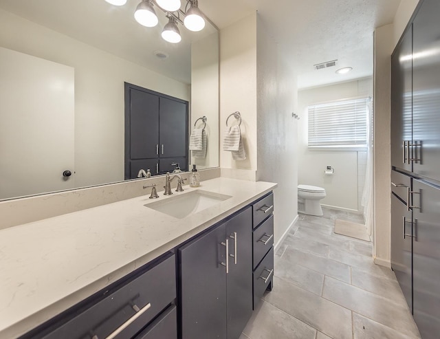 bathroom with tile patterned flooring, vanity, a chandelier, and toilet